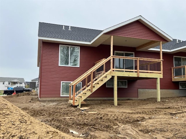 back of house featuring a deck, a shingled roof, and stairs