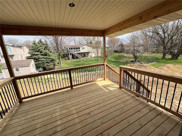 wooden terrace featuring a lawn, a residential view, and an outdoor structure