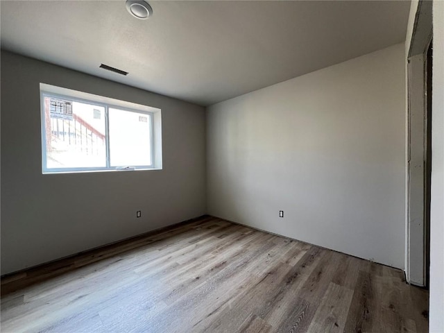 unfurnished room with wood finished floors and visible vents