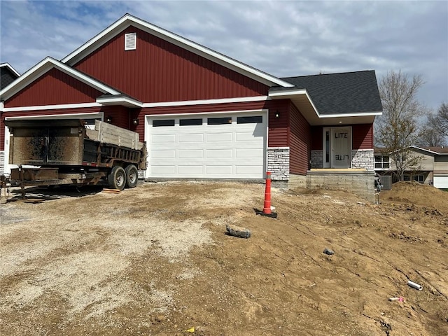craftsman-style house featuring a garage, driveway, and stone siding