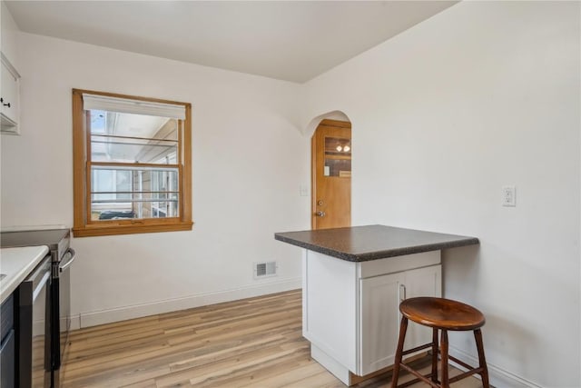 kitchen with a breakfast bar, light wood-type flooring, white cabinetry, and kitchen peninsula