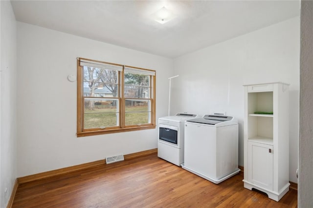 washroom with washing machine and dryer and light hardwood / wood-style floors