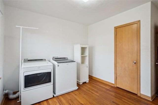 clothes washing area featuring washer and clothes dryer and wood-type flooring