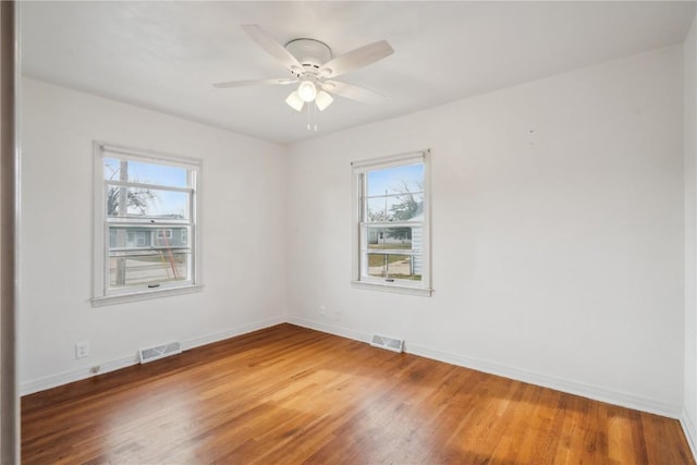 empty room featuring hardwood / wood-style flooring, ceiling fan, and a wealth of natural light