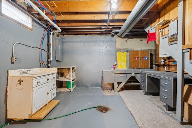 basement with a workshop area, sink, and electric panel