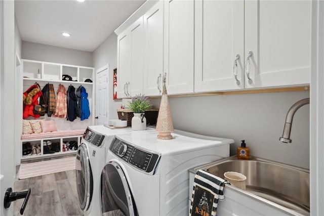 washroom featuring cabinets, separate washer and dryer, sink, and light hardwood / wood-style flooring