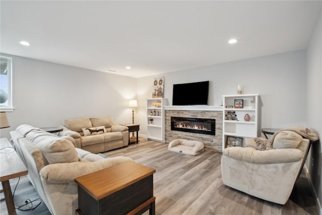 living room featuring a stone fireplace and light hardwood / wood-style flooring