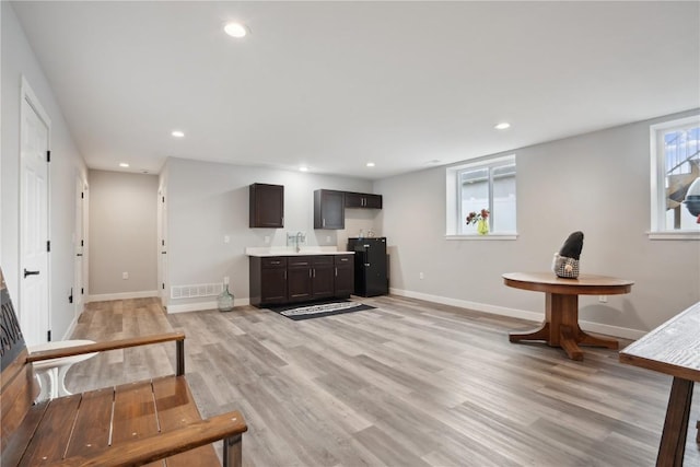 bar with dark brown cabinetry, sink, and light wood-type flooring