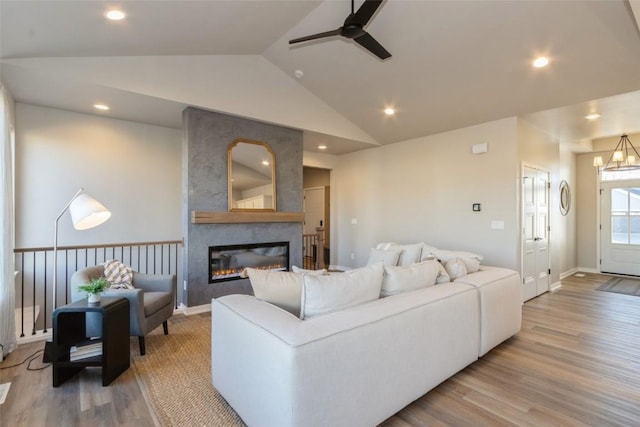 living room featuring hardwood / wood-style floors, ceiling fan with notable chandelier, lofted ceiling, and a fireplace