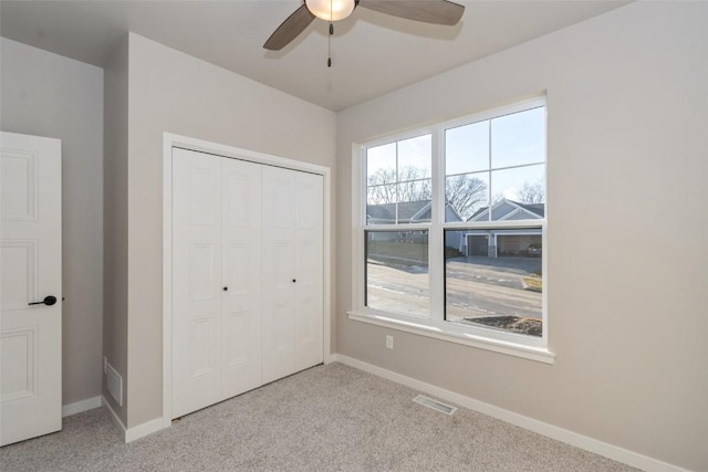 unfurnished bedroom featuring light carpet, a closet, and ceiling fan