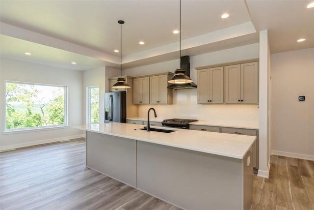 kitchen with sink, wall chimney exhaust hood, stainless steel fridge, decorative light fixtures, and light wood-type flooring