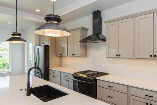 kitchen featuring gas stove, sink, hanging light fixtures, wall chimney range hood, and stainless steel fridge with ice dispenser