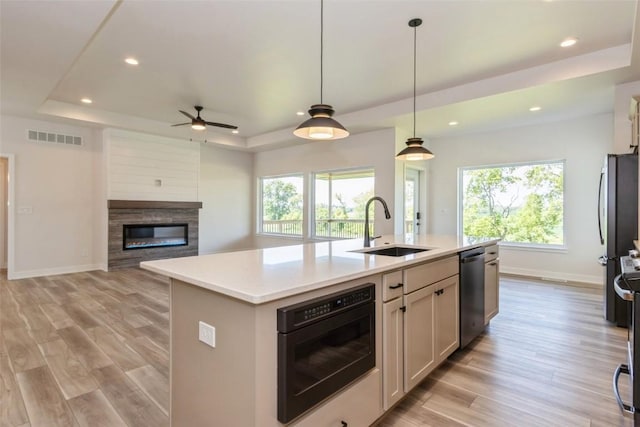 kitchen with a wealth of natural light, sink, a center island with sink, and appliances with stainless steel finishes