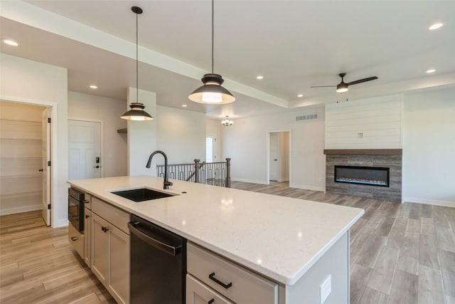 kitchen with white cabinetry, stainless steel dishwasher, light hardwood / wood-style floors, decorative light fixtures, and a center island with sink