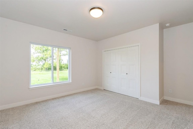 unfurnished bedroom featuring light colored carpet and a closet