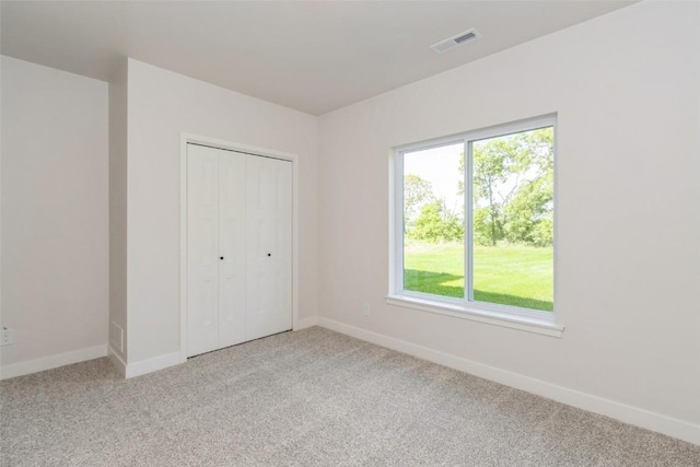 unfurnished bedroom with light carpet and a closet