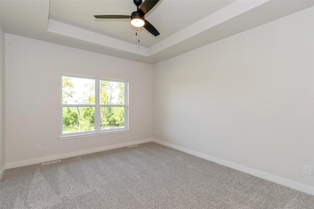 carpeted empty room featuring ceiling fan and a tray ceiling