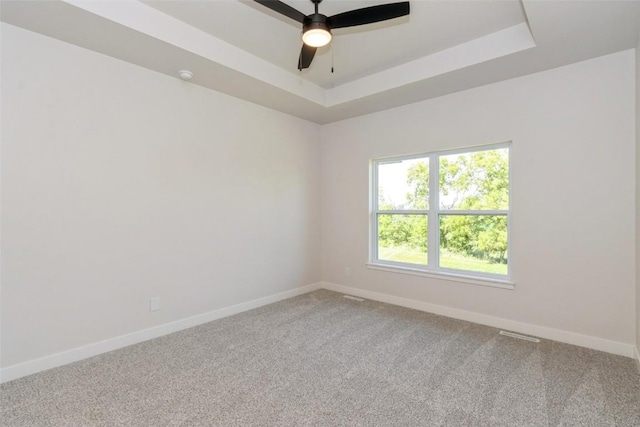 unfurnished room with ceiling fan, a raised ceiling, and carpet floors