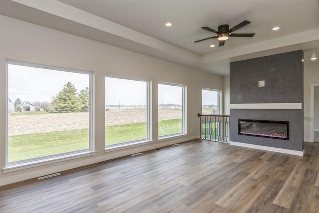 unfurnished living room with a wealth of natural light, a fireplace, ceiling fan, and light hardwood / wood-style floors