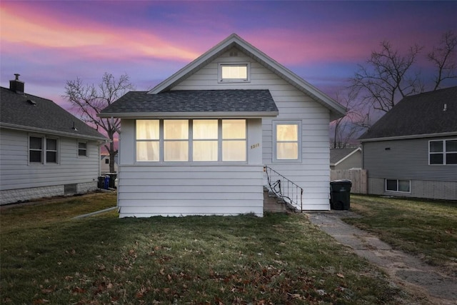 back house at dusk featuring a yard