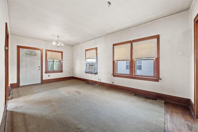 unfurnished room featuring hardwood / wood-style flooring, cooling unit, ornamental molding, and an inviting chandelier