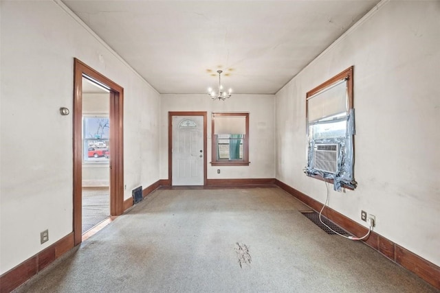 interior space with light carpet, ornamental molding, and a notable chandelier