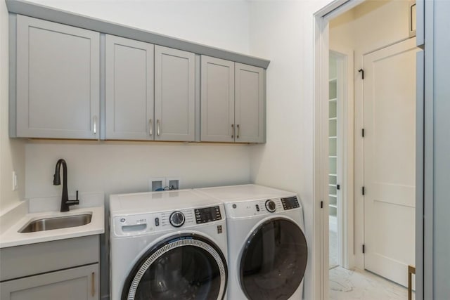 laundry area featuring cabinets, separate washer and dryer, and sink