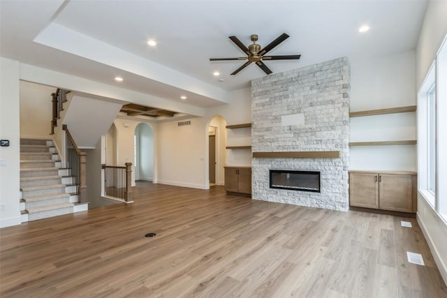 unfurnished living room with ceiling fan, light hardwood / wood-style floors, and a fireplace