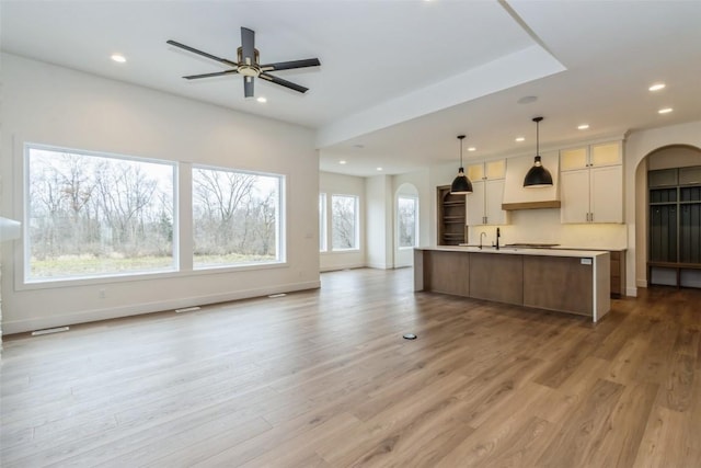 kitchen with white cabinets, pendant lighting, light wood-type flooring, and a spacious island