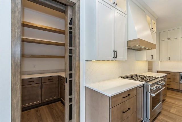 kitchen with high end range, custom range hood, light hardwood / wood-style floors, and white cabinets