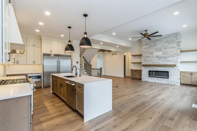 kitchen featuring built in appliances, a large island, light hardwood / wood-style flooring, and decorative light fixtures