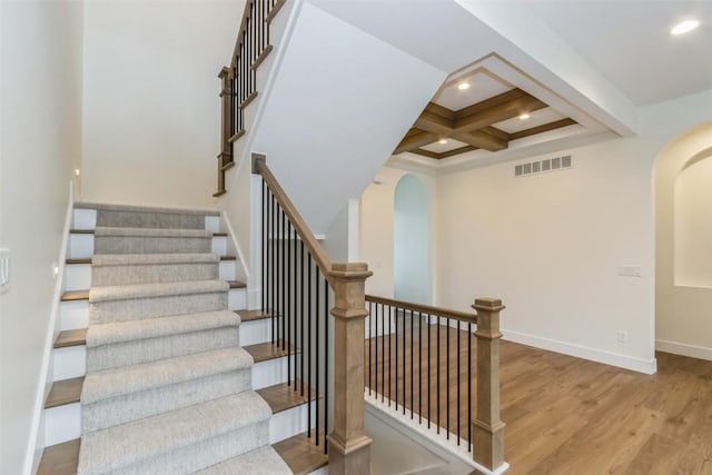 stairs featuring hardwood / wood-style flooring, beam ceiling, and coffered ceiling