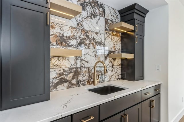 kitchen with decorative backsplash, light stone counters, and sink