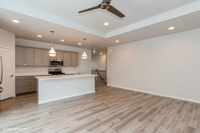 kitchen featuring stainless steel appliances, hanging light fixtures, gray cabinetry, and light hardwood / wood-style floors