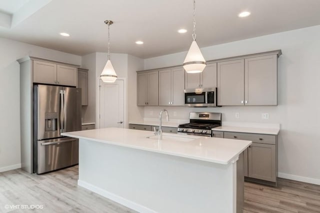 kitchen featuring gray cabinets, a center island with sink, light hardwood / wood-style floors, and appliances with stainless steel finishes