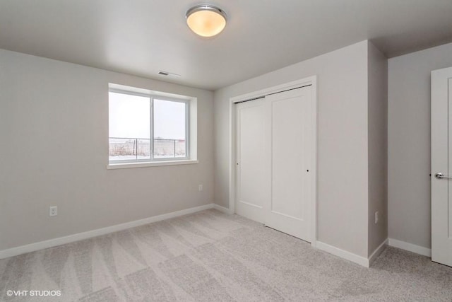 unfurnished bedroom featuring a closet and light colored carpet