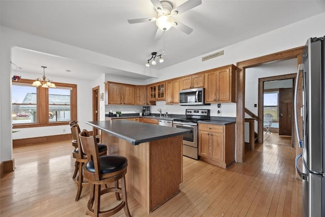 kitchen featuring a center island, stainless steel appliances, a kitchen breakfast bar, light hardwood / wood-style floors, and decorative light fixtures