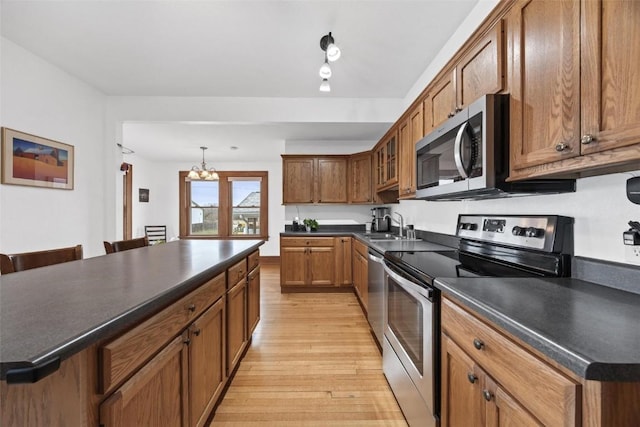 kitchen featuring a kitchen bar, stainless steel appliances, a chandelier, light hardwood / wood-style floors, and a kitchen island