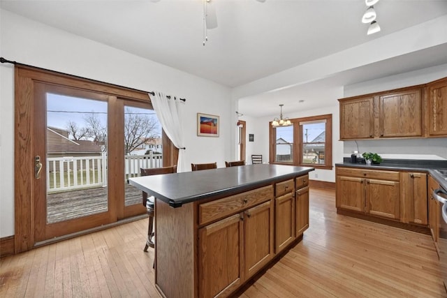 kitchen with a kitchen island, decorative light fixtures, light hardwood / wood-style flooring, and a breakfast bar area