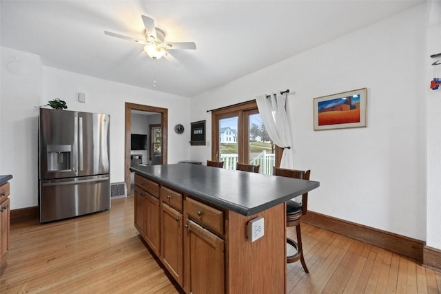 kitchen with ceiling fan, a center island, stainless steel fridge with ice dispenser, and light hardwood / wood-style flooring