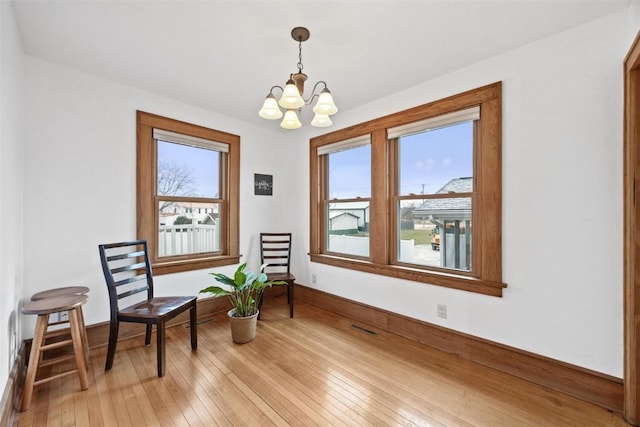 sitting room with plenty of natural light, hardwood / wood-style floors, and an inviting chandelier