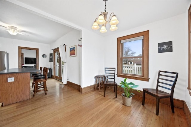 sitting room with ceiling fan with notable chandelier and light hardwood / wood-style floors