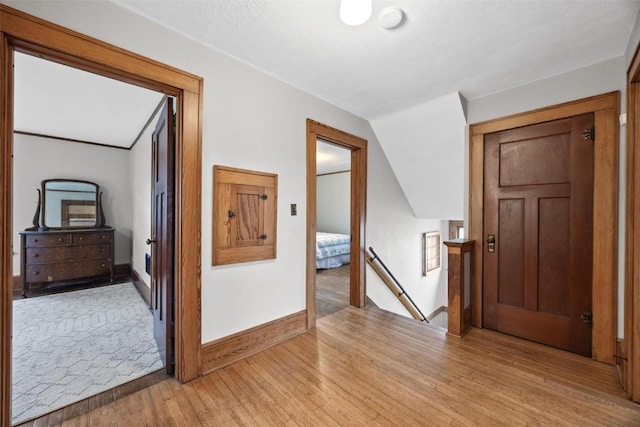 corridor featuring light hardwood / wood-style floors and lofted ceiling