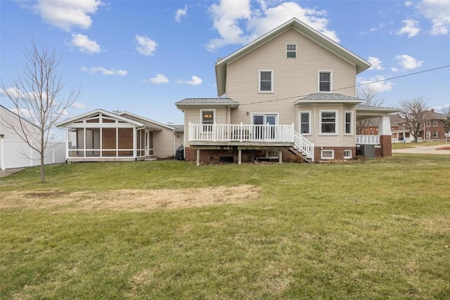 rear view of property with a sunroom, a wooden deck, and a lawn