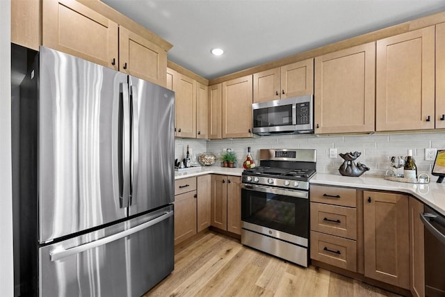 kitchen with decorative backsplash, light brown cabinets, light hardwood / wood-style floors, and appliances with stainless steel finishes