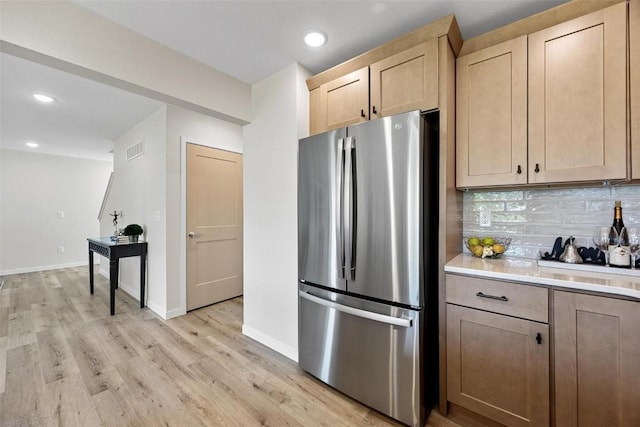 kitchen featuring backsplash, stainless steel fridge, light brown cabinetry, and light hardwood / wood-style flooring