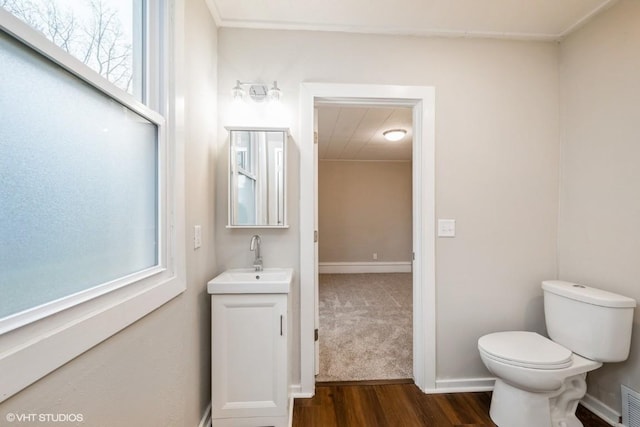 bathroom with hardwood / wood-style flooring, vanity, a healthy amount of sunlight, and toilet