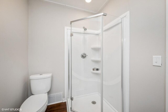 bathroom with hardwood / wood-style flooring, toilet, and an enclosed shower