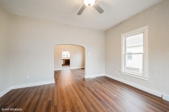 empty room featuring dark hardwood / wood-style floors, ceiling fan, and a textured ceiling