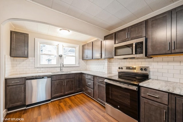 kitchen featuring dark brown cabinetry, sink, tasteful backsplash, dark hardwood / wood-style flooring, and appliances with stainless steel finishes